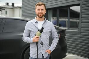 un hombre cargos su moderno eléctrico coche. el concepto de verde energía foto