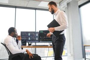 Two confident businessmen, financial analysts or investment advisers sitting at office desk photo