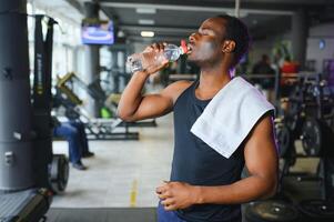 contento joven africano hombre Bebiendo agua después ejercicio foto