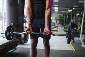 atlético negro chico haciendo levantamiento de pesas o levantamiento de pesas a moderno gimnasio foto