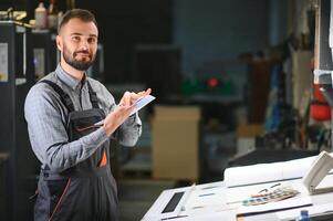 Print house worker controlling printing process quality and checking colors with magnifying glass photo