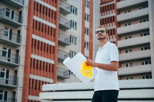 retrato de un arquitecto constructor estudiando diseño plan de el habitaciones, grave civil ingeniero trabajando con documentos en construcción sitio. foto