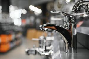 Water taps of different types and shapes on the counter in the store. Retail trade in sanitary ware. Foreground. photo