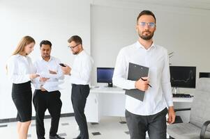 Team leader stands with coworkers in background photo