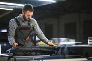 Print worker trying to fix the problem on computer to plate machine in printing shop photo