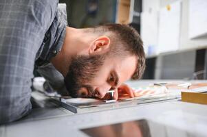 Print house worker controlling printing process quality and checking colors with magnifying glass photo