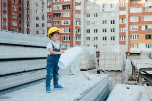 Architect in helmet writing something near new building. little cute boy on the building as an architect photo