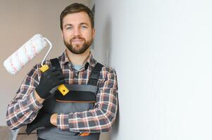 Painter painting a wall with paint roller. Builder worker painting surface with white color photo