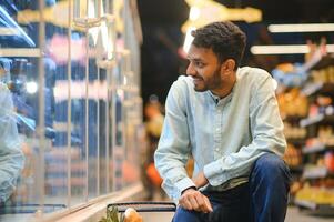 Portrait of happy handsome young Indian at grocery shop or supermarket. photo