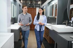 Young couple choosing new bathroom furniture at the plumbing shop with lots of sanitary goods photo