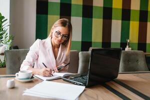 Portrait of young attractive businesswoman examining paperwork in bight light office interior sitting next to the window, business woman read some documents before meeting, filtered image. photo