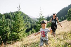 joven mamá con bebé chico de viaje. madre en excursionismo aventuras con niño, familia viaje en montañas. nacional parque. caminata con niños. activo verano vacaciones. ojo de pez lente. foto