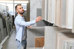 Young man choosing tiles at building market photo