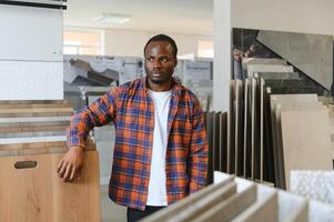 African american man customer choosing ceramic tile at building materials store photo
