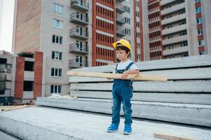 arquitecto en casco escritura alguna cosa cerca nuevo edificio. pequeño linda chico en el edificio como un arquitecto. foto