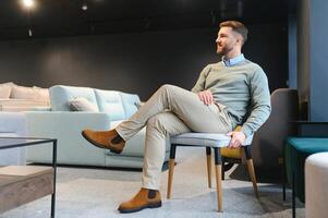 Young man looking for new chair for home at furniture warehouse photo