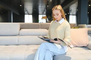 mujer diseñador a mueble Tienda mirando a textil muestra de tela foto