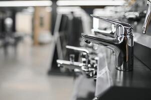 Water taps of different types and shapes on the counter in the store. Retail trade in sanitary ware. Foreground. photo