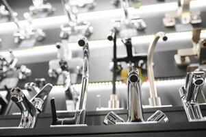 Water taps of different types and shapes on the counter in the store. Retail trade in sanitary ware. Foreground. photo