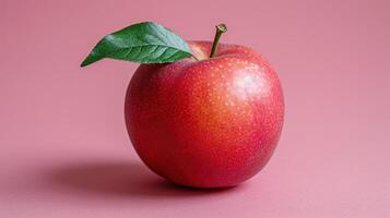 Red apple with green leaf on vibrant pink backdrop photo