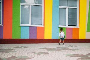 Back to school. Happy smiling boy in glasses is going to school for the first time. Child with backpack and book outdoors. Beginning of lessons. First day of fall. photo