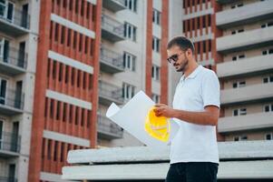 retrato de un arquitecto constructor estudiando diseño plan de el habitaciones, grave civil ingeniero trabajando con documentos en construcción sitio. foto