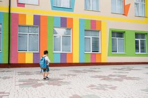 pequeño chico yendo espalda a escuela. niño con mochila y libros en primero colegio día. espalda vista. colegio concepto. espalda a escuela. foto