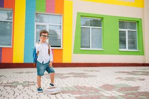 linda colegial en blanco camisas y un lentes con libros y un mochila. espalda a escuela. foto