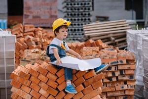 Architect in helmet writing something near new building. little cute boy on the building as an architect photo