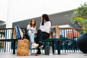 Beautiful young mom and teenage daughter are holding shopping bags, shopping in mall. Family shopping. photo