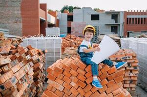 arquitecto en casco escritura alguna cosa cerca nuevo edificio. pequeño linda chico en el edificio como un arquitecto. foto