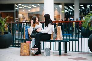 hermosa joven mamá y Adolescente hija son participación compras pantalones y sonriente mientras haciendo compras en centro comercial. familia compras foto