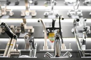 Water taps of different types and shapes on the counter in the store. Retail trade in sanitary ware. Foreground. photo