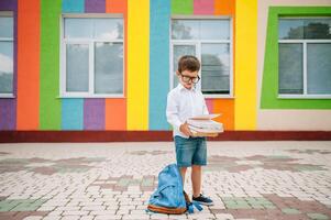 Cute schoolboy in white shirts and a glasses with books and a backpack. Back to school. photo