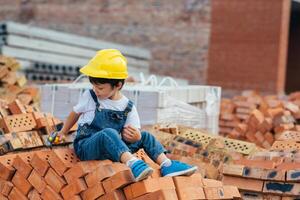 Architect in helmet writing something near new building. little cute boy on the building as an architect photo