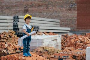 Architect in helmet writing something near new building. little cute boy on the building as an architect photo