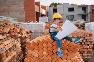 Architect in helmet writing something near new building. little cute boy on the building as an architect. photo