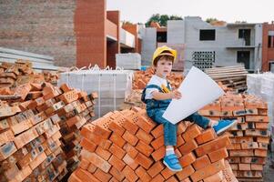 Architect in helmet writing something near new building. little cute boy on the building as an architect. photo
