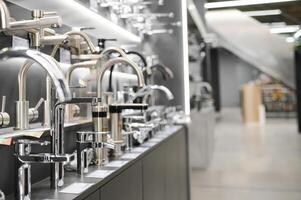 Water taps of different types and shapes on the counter in the store. Retail trade in sanitary ware. Foreground. photo