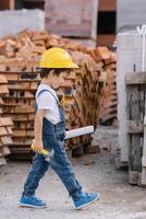 Architect in helmet writing something near new building. little cute boy on the building as an architect photo