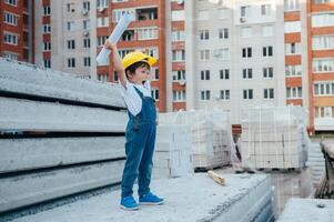 arquitecto en casco escritura alguna cosa cerca nuevo edificio. pequeño linda chico en el edificio como un arquitecto foto