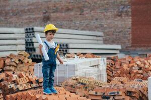 Architect in helmet writing something near new building. little cute boy on the building as an architect photo