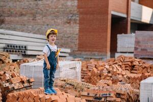 Architect in helmet writing something near new building. little cute boy on the building as an architect photo