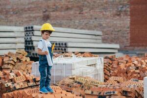 Architect in helmet writing something near new building. little cute boy on the building as an architect photo