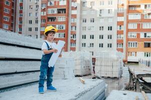 Architect in helmet writing something near new building. little cute boy on the building as an architect photo