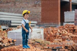 Architect in helmet writing something near new building. little cute boy on the building as an architect photo