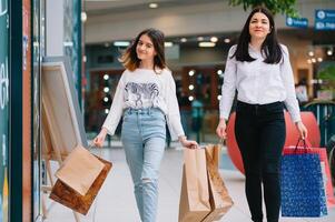 hermosa joven mamá y Adolescente hija son participación compras bolsas, compras en centro comercial. familia compras foto