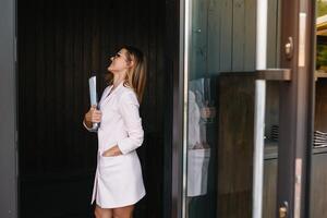 Portrait of a successful businesswoman holding a digital tablet pad and a folder while proudly standing near office. photo