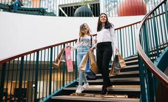 hermosa joven mamá y Adolescente hija son participación compras bolsas, compras en centro comercial. familia compras foto