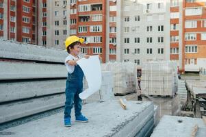 arquitecto en casco escritura alguna cosa cerca nuevo edificio. pequeño linda chico en el edificio como un arquitecto. foto